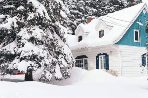 Scene of a house after a heavy snowfall, with several feet of snow piled up outside